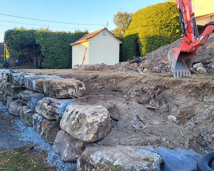 Excavation du terrain et installations des pierres pour le mur de soutènement